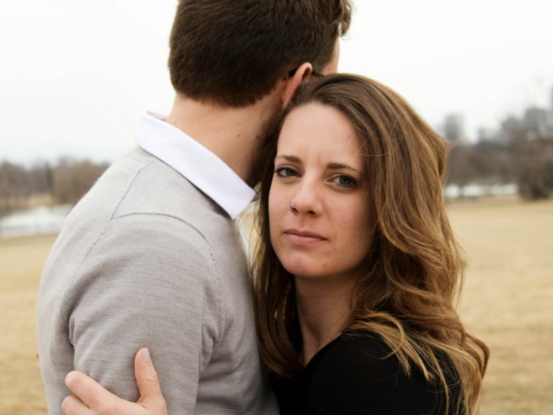 couple hugging, woman looking serious