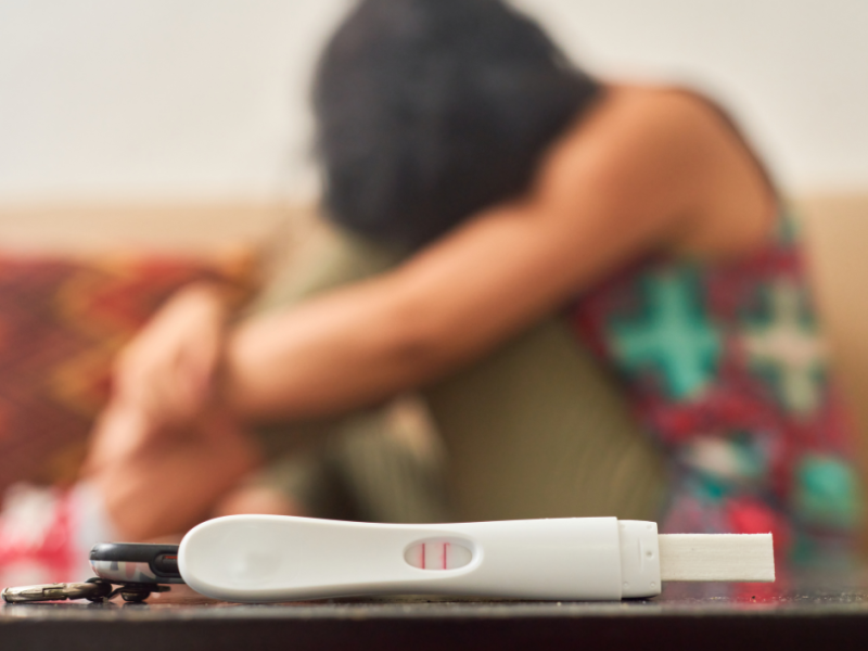 positive pregnancy test and sad woman