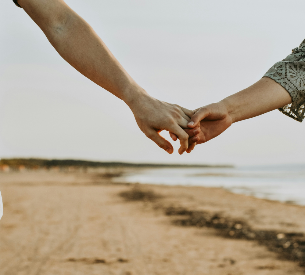 A couple gently holding hands, offering each other comfort and support. Their hands rest on a bench, symbolizing togetherness during a difficult time, such as coping with pregnancy loss.